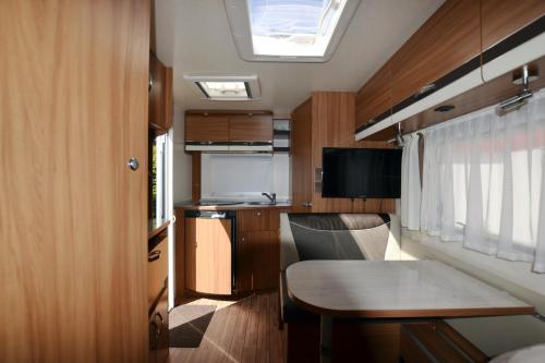 a small kitchen and dining room in a tiny house at Mietwohnwagen Samson Fehmarn in Fehmarn