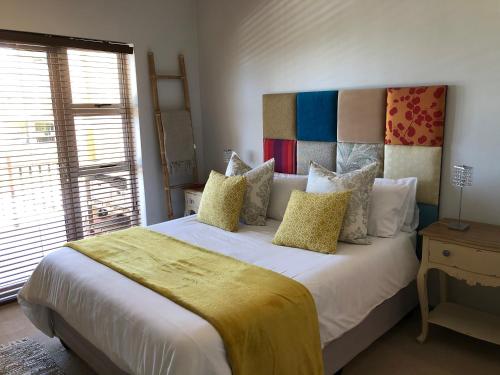 a bedroom with a large bed with a yellow blanket on it at Goose Valley Retreat with Sea Views in Plettenberg Bay