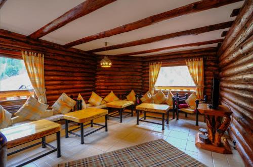 a living room with wooden walls and couches and windows at Resort Cheile Gradistei Moieciu in Moieciu de Sus