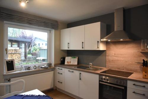 uma cozinha com armários brancos, um lavatório e uma janela em Sylvia Helene Lafrenz em Winkl bei Grabenstätt