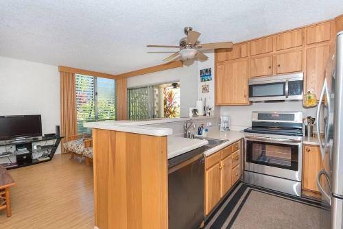 a kitchen with wooden cabinets and a ceiling fan at Enjoy the sunset at OCEAN FRONT 1BR Apartment - pool on site! in Kailua-Kona