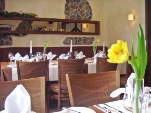 a restaurant with tables and chairs and a yellow flower at Hotel Eifelstube in Rodder