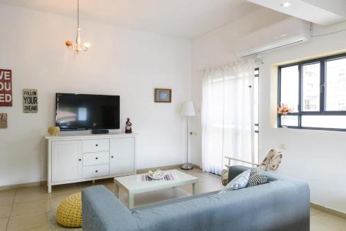 sala de estar con sofá azul y TV en Judith's Place - Stylish Apartments en Ramat Gan