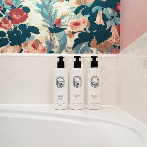 three shampoo bottles sitting on a shelf in a bathroom at Palihouse Santa Barbara in Santa Barbara