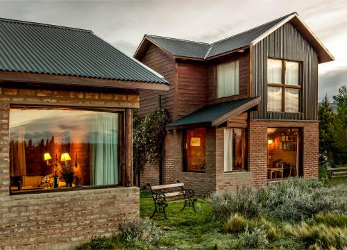 a house with a bench in front of a window at Posada Larsen in El Calafate