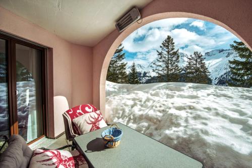 a room with a table and a window with snow at Haus Belvédère in Arosa