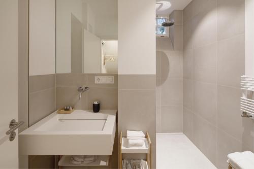 Boutique Apartments Freiburg - Eva في فريبورغ ام بريسغاو: حمام أبيض مع حوض ومرآة