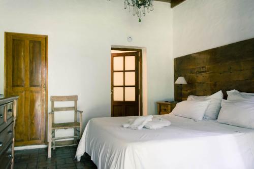 - une chambre avec un lit blanc et une tête de lit en bois dans l'établissement Estancia La Cinacina, à San Antonio de Areco