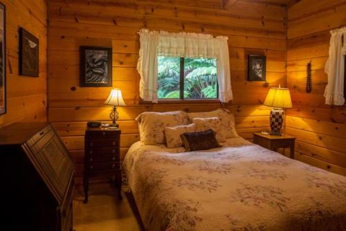 a bedroom with a bed in a log cabin at Cymbidium House Volcano Village by Casago Kona - Fun! in Volcano