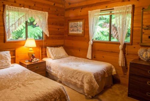 a bedroom with two beds in a log cabin at Cymbidium House Volcano Village by Casago Kona - Fun! in Volcano