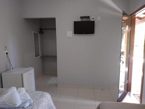 a white room with a bed and a television at Suites do Ratinho in Pirenópolis