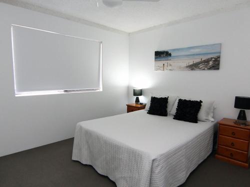 a white bedroom with a bed and a window at The Breakers 8 in Forster