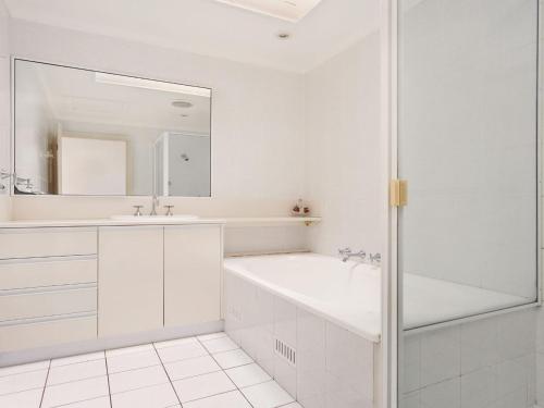 een witte badkamer met een bad, een wastafel en een spiegel bij Coral Sands 3 Pebbly Beach in Forster