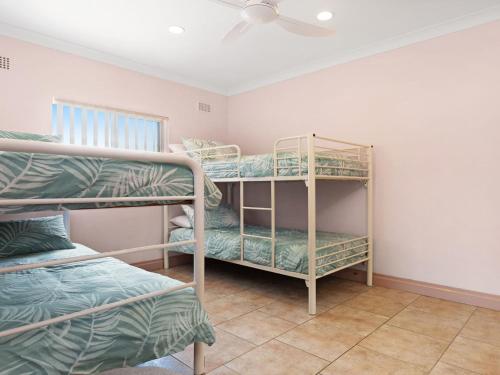 a room with two bunk beds and a ceiling fan at Debra Court 11 in Forster