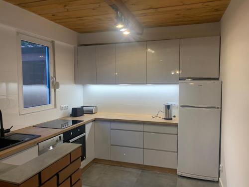 a kitchen with white cabinets and a white refrigerator at Dom nad jeziorem margonińskim Sport & Wypoczynek in Klotyldzin