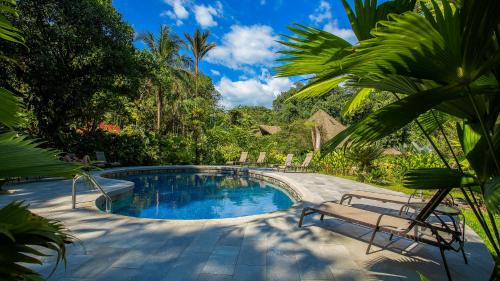 a swimming pool with two chairs and a bench at Esquinas Rainforest Lodge in Golfito