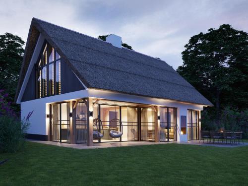 een groot huis met een gambrel dak bij Luxury villa with sauna only a few minutes from the beach in De Cocksdorp