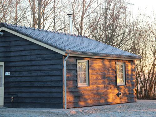 una pequeña cabaña de madera con dos ventanas. en Cozy vacation home with terrace, en Lage Zwaluwe