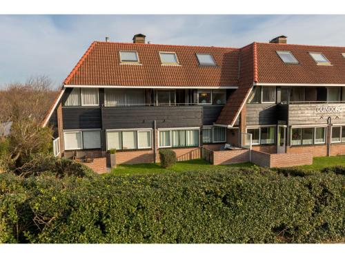 een groot huis met een rood dak bij Attractive holiday home in Zoutelande near center in Zoutelande