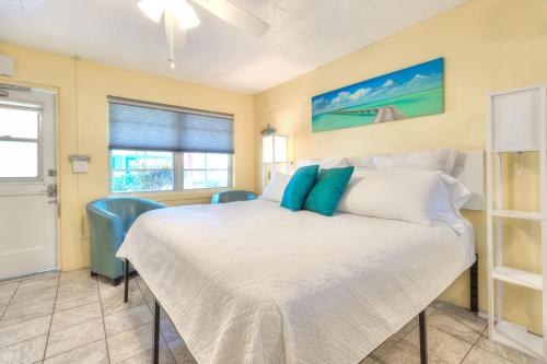 1 dormitorio con 1 cama blanca y sillas azules en Tropic Terrace #22 - Beachfront Rental condo, en St Pete Beach