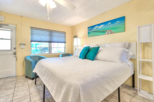 a bedroom with a white bed and blue chairs at Tropic Terrace #22 - Beachfront Rental condo in St Pete Beach