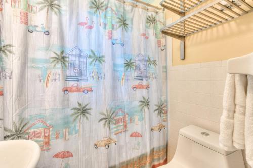 a bathroom with a shower curtain with palm trees at Tropic Terrace #22 - Beachfront Rental condo in St Pete Beach