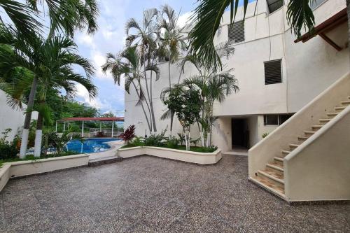 an external view of a building with palm trees and a swimming pool at 64 Peninsula del Capitan in Manzanillo