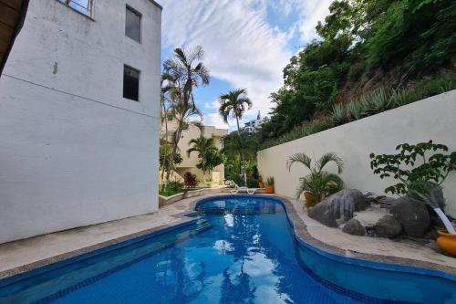 a swimming pool next to a white building with trees at 64 Peninsula del Capitan in Manzanillo