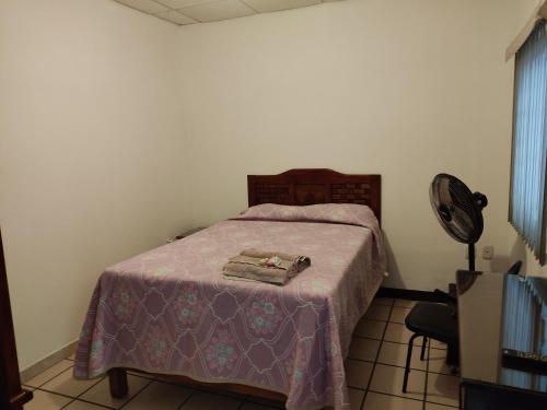 a bedroom with a bed with a purple blanket and a fan at Hostal Herencia in Tequila