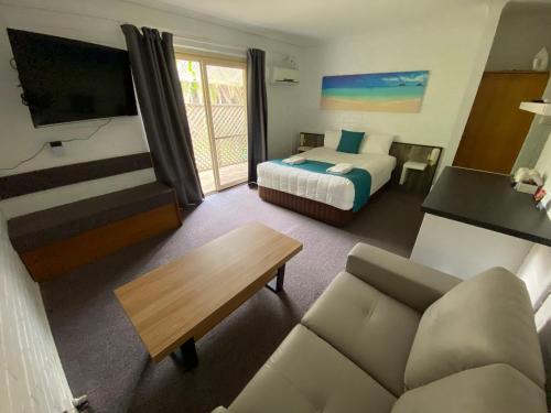 een hotelkamer met een bed en een bank bij Top of the Town Motor Inn in Narooma