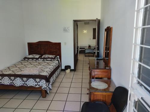 a bedroom with a bed and a table and a mirror at Hostal Herencia in Tequila