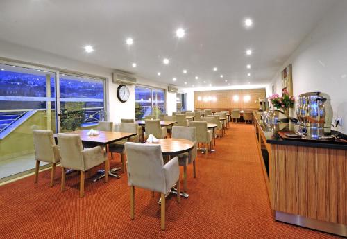 a dining room with tables and chairs and a clock at Kardes Hotel in Bursa