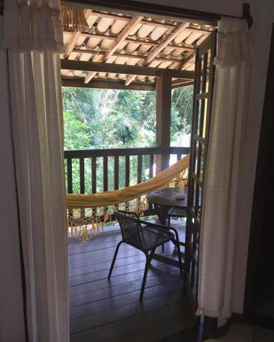 a screened in porch with a hammock and a table at MangoBrazil in Imbassai