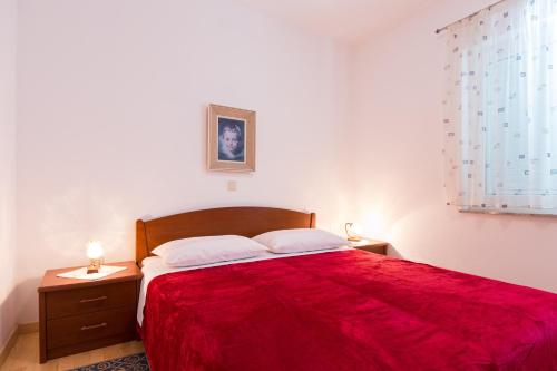 - une chambre avec un grand lit rouge et 2 tables de chevet dans l'établissement Apartman Leana, à Krk
