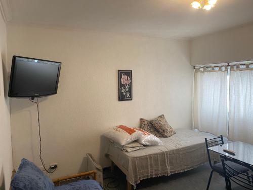 Habitación pequeña con cama y TV en la pared. en av. Colón Apartamento en Mar del Plata