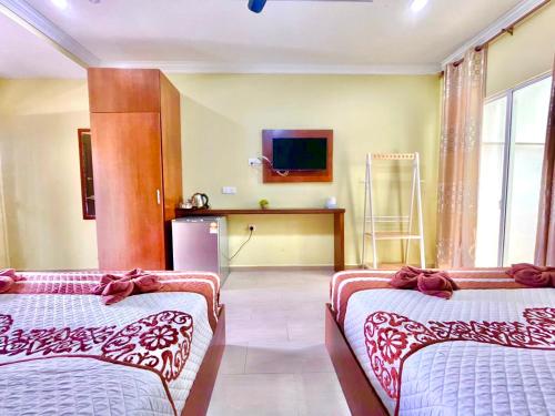 Habitación de hotel con 2 camas y TV en Norshah Village Resort en Pantai Cenang