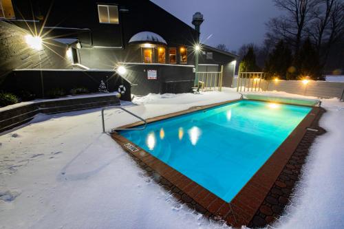una piscina coperta di neve di fronte a una casa di Mountain Inn at Killington a Killington