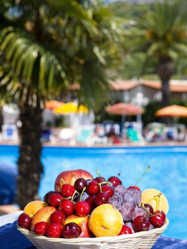 a basket of fruit on a table near a pool at Hotel Terme Park Imperial in Ischia