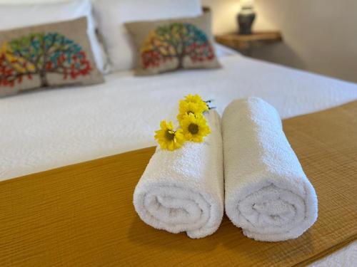 a pair of towels with a flower on a bed at Casa Hridaya Hotel Boutique in Holbox Island