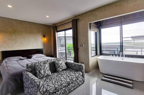 a bedroom with a bed and a bath tub and a chair at Lounge in Loft HuaHin Pool Villa บ้านพักในหัวหิน in Ban Wang Bot