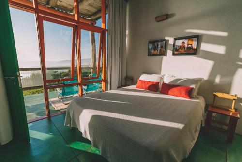 um quarto com uma cama grande e uma janela grande em Pousada Pedra Grande na Praia do Rosa
