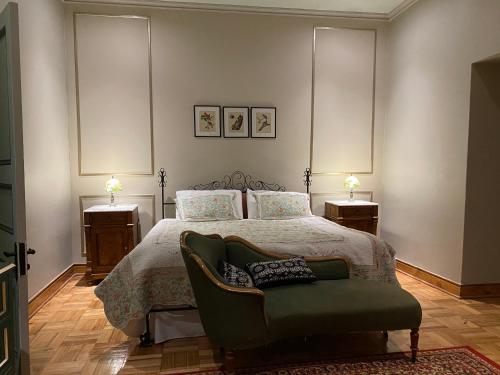 a bedroom with a bed and a green chair at Casona Lo Aguirre , Hospedaje de Temporada Cálidas in Talagante