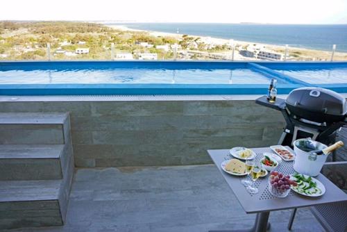 una mesa con parrilla y platos de comida en el balcón en SYRAH Piscina Privada y Vista al Mar en Punta Ballena, en Punta del Este