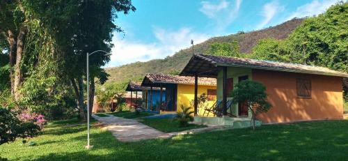 una pequeña casa amarilla con una colina al fondo en Chalés Jardim da Serra, en Serra do Cipo