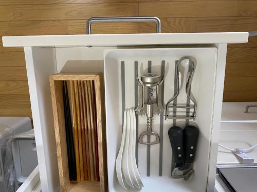 un armadietto bianco con utensili da cucina di KR バーズ ヴィラ伊豆白浜リゾート a Shimoda