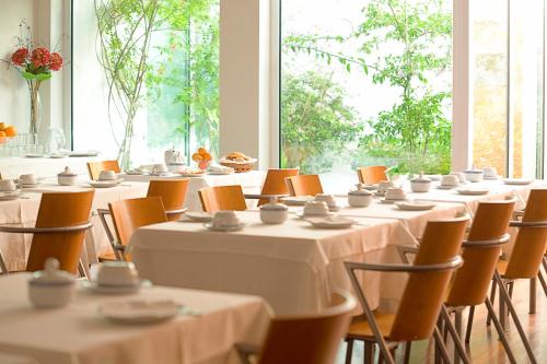 Costa Nova Hotel في كوستا نوفا: غرفة بها طاولات وكراسي عليها صحون واكواب
