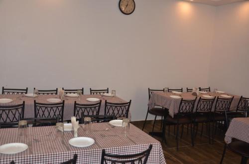 a room with tables and chairs and a clock on the wall at Hotel Krishna in Katra