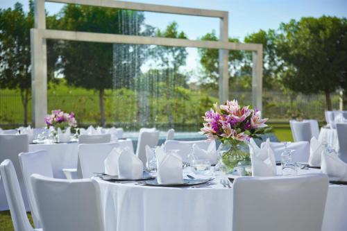a group of tables with white chairs and flowers on them at Park Arjaan by Rotana, Abu Dhabi in Abu Dhabi