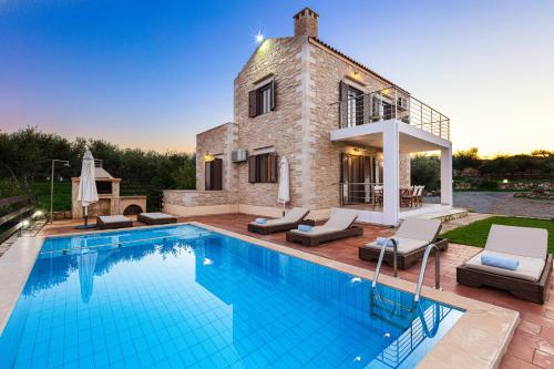 a villa with a swimming pool in front of a house at Dimokritos Villas, a homestay experience, By ThinkVilla in Angeliana