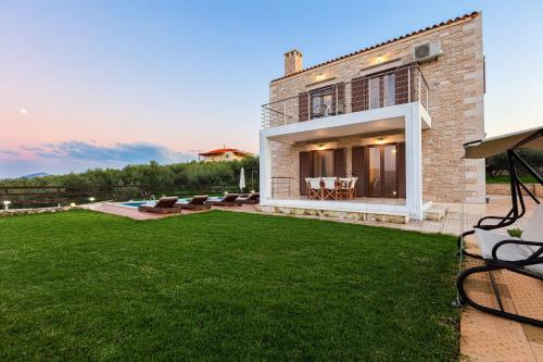 a house with a lawn in front of it at Dimokritos Villas, a homestay experience, By ThinkVilla in Angeliana